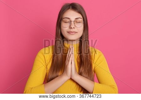Portrait Of Peaceful Positive Good Looking Girl Closing Eyes, Putting Hands Together, Having Calm Fa