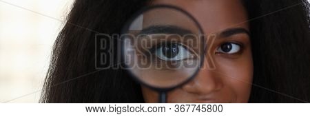 Attractive Girl Looking Through Magnifier, Smiling. Close-up Face Dark-skinned Woman With Her Hair. 