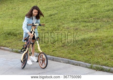 A Beautiful Young Woman Folds Up And Unfolds A Bicycle. Convenient Folding Bike For Travel And Trans