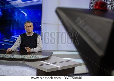 A Male News Anchor In A Broadcast Studio Reads Text On A Teleprompter. Camera In The Tv Studio.