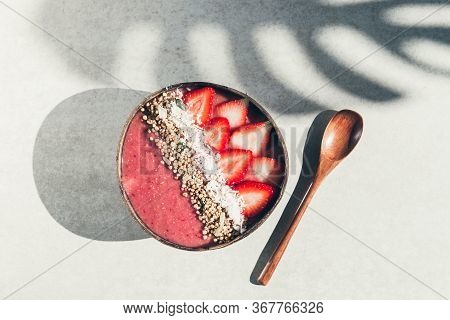 Pink Smoothie From Banana And Strawberries With Pieces Of Strawberries, Granola And Coconut Shreds O