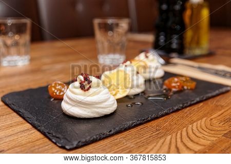 Meringue dessert with orange chips and leechee jam on restaurant table