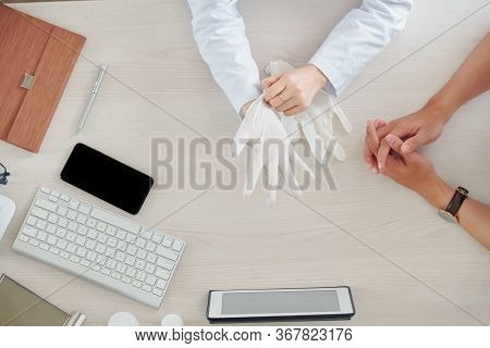 General Practitioner Putting On Rubber Gloves Before Palpating Patient During Annual Chack-up, View 