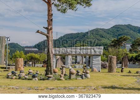 Gimcheon, South Korea; May 24, 2020: Tree In Middle Of Stone Stacks With Stone Gate Structure In Bac