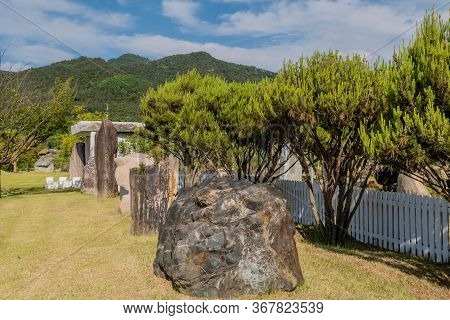 Gimcheon, South Korea; May 24, 2020: Granite Boulder And Large Section Of Petrified Tree Trunk In Fr