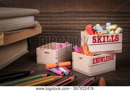 Skills And Knowledge Concept. Colored Papr Scrolls In Wooden Boxes On Dark Wooden Background