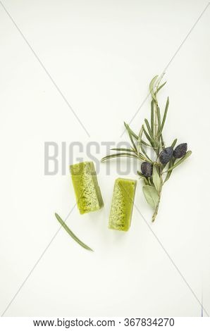An Olive Branch And Handmade Olive Soap Bars On White Background With Copyspace.
