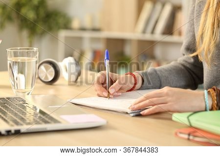 Close Up Of Student Girl Hands Writing On Notebook Doing Homework Stting On A Desk