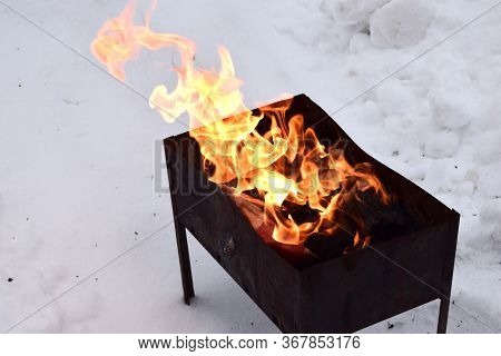 Coals Burning Wood And Bokeh Fire Ash Blaze Mangal Barbeque. Small Mangal With Flame In Forest. Camp