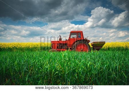 Red Tractor In A Field And Dramatic Clouds