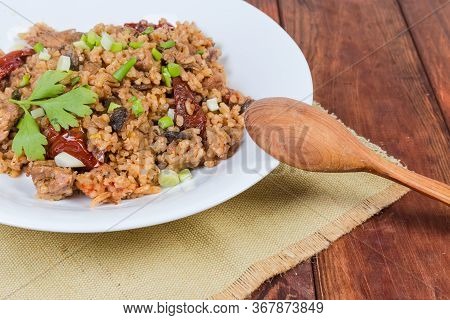 Cooked Paella With Meat And Mushroms On The White Dish With Wooden Spoon On Napkin On The Rustic Tab