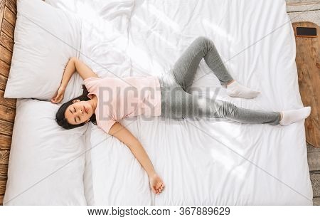 Asian Woman Sleeping In Funny Pose Lying On Back In Bed At Home. Good Sleep Concept. Top View