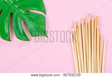 Wheat Straw For Drinking Water With Green Leaves On Pink Background. Zero Waste Concept.