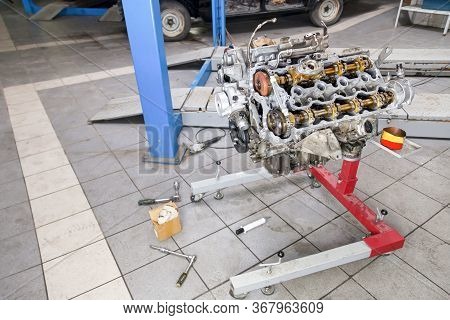 An Iron Large Engine Shot With Eight Cylinders On A Special Red Stand In A Car Service Against A Bac