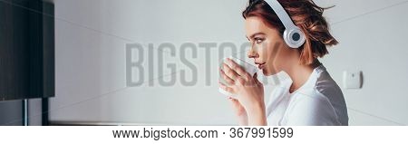 Beautiful Girl Drinking Coffee And Listening Music With Headphones In Bed During Self Isolation, Pan