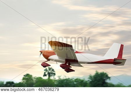 Sport Monoplane Flying Near Trees Under Sky