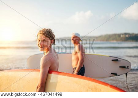 Smiling Teen Boy With Surfboard Go To The Sea For Surfing. He Have A Winter Vacation And Enjoying A