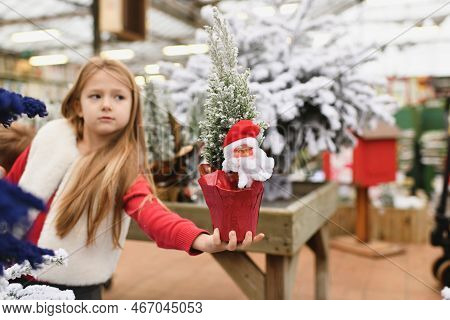 Girl Holding An Artificial Christmas Tree With Santa Claus