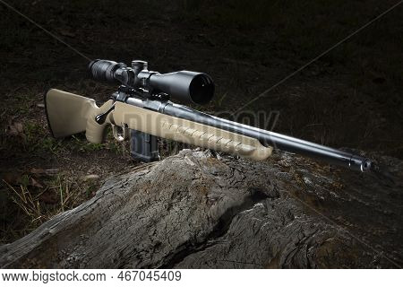 Brown Bolt Action Rifle In 556 With A Scope On A Log In The Forest