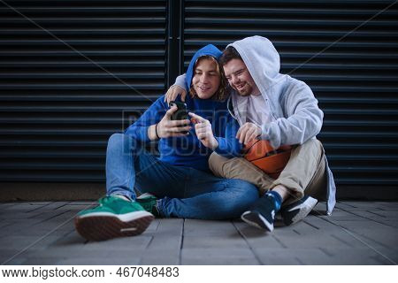 Man With Down Syndrome Resting During Basketball Playing Outdoor With His Friend. Concept Of Friends