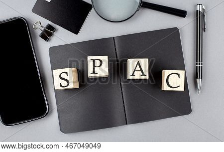 Word Spac, Special Purpose Acquisition Company Symbol On Wooden Block On A Black Notebook With Smart