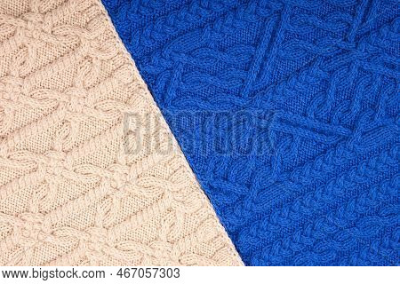 Knitted Blue And Beige Background. Large Knitted Fabric With A Pattern. Close-up Of A Knitted Blanke