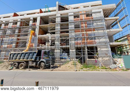 Yellow Long Plastic Tube Placed Next To Building Under Construction For Throwing Industrial Waste In