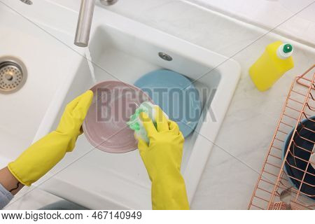 Woman Washing Plate Above Sink In Modern Kitchen, Top View