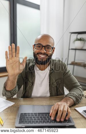 Greeting Concept. Portrait Of Happy Freelancer Man Waving Hello At Webcamera, Using Laptop And Video