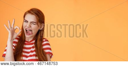 Sassy Asserive Relaxed Redhead Woman Assuring Everything Under Control, Make Deal, Wink Show Tongue 