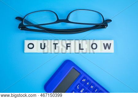Calculator And Paper Money With The Word Outflow. Outflow Concept. Cash Flow Concept