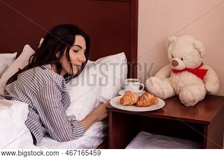 A Young Beautiful Girl Sleeps With A Teddy Bear In A Bed In Pajamas