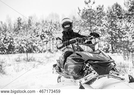 A Man Is Riding Snowmobile In Mountains. Pilot On A Sports Snowmobile In A Mountain Forest. Black An