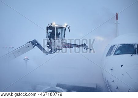 Deicing Of Airplane Before Flight. Winter Day At Airport During Snowfall.