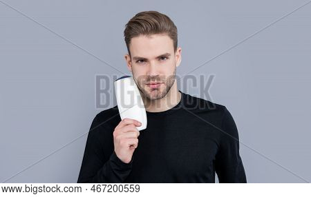 Portrait Of Man Hold Unbranded Cosmetics Isolated On Grey Background. Man With Unbranded Cosmetic
