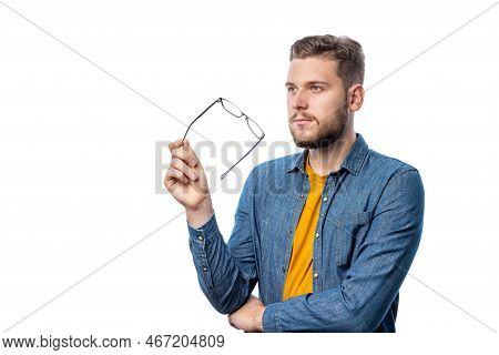 Handsome Pensive Bearded Male In Casual Cothing Holding Eyeglasses Isolated On White Background