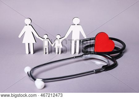 Figures Of Family Stainding Near Stethoscope And Heart On Lilac Background. Insurance Concept