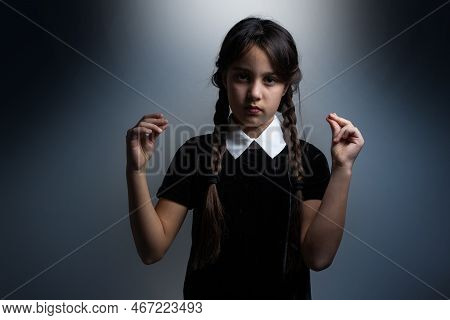 Portrait Of Little Girl With Wednesday Addams Costume During Halloween. Serious Expression And Dark 
