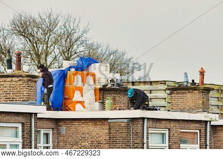 Den Haag, Netherlands - January 06 2022: A Roofer Is On The Roof Of A Home With A Flat Roof Replacin