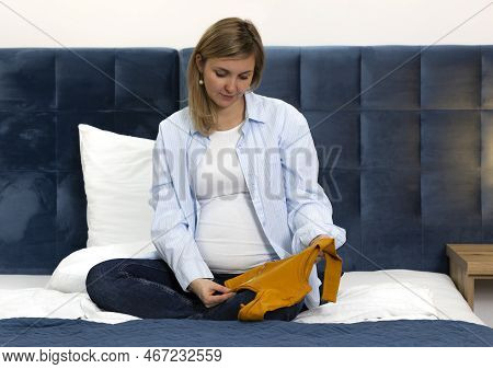 Happy Pregnant Woman Holds Orange Baby Starter Kit, Unisex Baby Long-sleeve Bodysuit Set, Sitting On