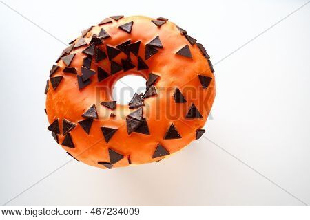 Halloween Donut With Orange Frosting And Chocolate Triangles As A Sweet Decorative Topping. Children