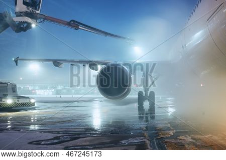 Deicing Of Airplane Before Flight. Winter Night At Airport During Snowfall.