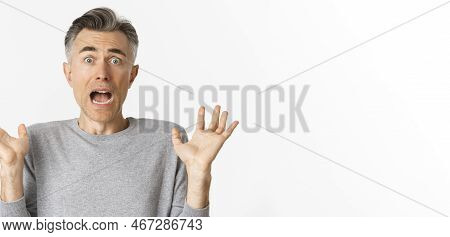Close-up Of Scared Middle-aged Man, Looking Startled, Jumping And Screaming Frightened, Standing Amb