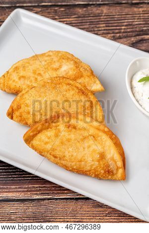 Beef Cheburek On A Wooden Table. Deep Fried Beef Dumplings With Meat And Onions. Turkish Name Ci Bor