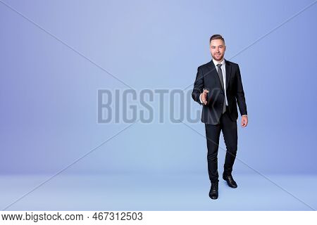 Smiling Handsome Businessman Wearing Formal Suit Standing Lending Hand For Handshake Near Empty Blue
