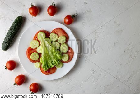 Sliced Tomatoes And Cucumbers Are In A White Plate. Nearby Are Unsliced Cucumbers And Tomatoes. Heal