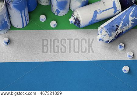 Sierra Leone Flag And Few Used Aerosol Spray Cans For Graffiti Painting. Street Art Culture Concept,