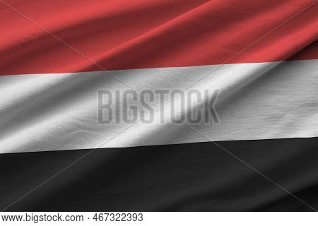 Yemen Flag With Big Folds Waving Close Up Under The Studio Light Indoors. The Official Symbols And C