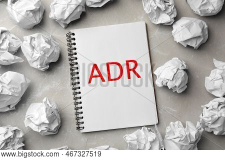Alternative Dispute Resolution. Notebook With Abbreviation Adr Surrounded By Paper Balls On Light Gr