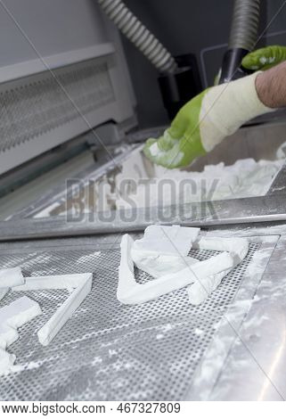 Male Worker Taking Out Models From White Polyamide Powder In Working Chamber Of 3d Printer, Cleaning